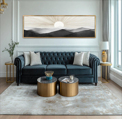 A modern living room with a blue tufted sofa, two round coffee tables, and a large framed landscape painting on the wall.