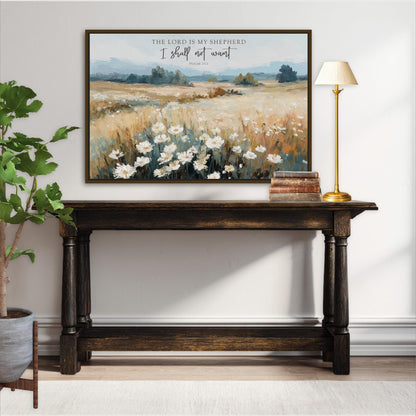 a wooden console table with a framed painting of a field of flowers hanging above it. The painting is titled "The Lord is my shepherd" and includes a Bible verse from Psalm 23. The console table is situated in a room with a lamp and a potted plant, creating a cozy and inviting atmosphere.