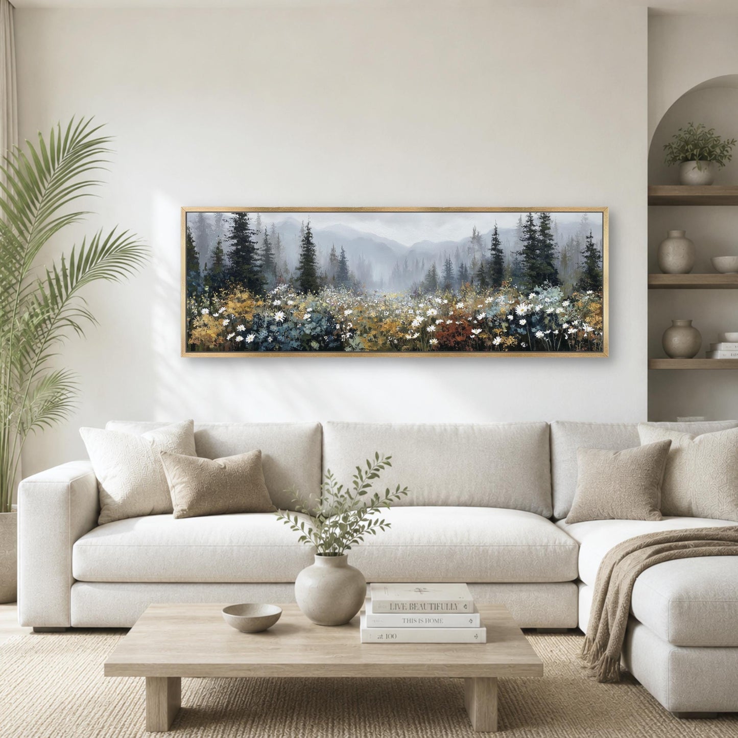 a serene living room with a large painting of a forest scene hanging on the wall above a white sofa. The painting features a variety of trees and flowers, creating a peaceful and natural atmosphere. The room is decorated with a wooden coffee table, a vase with greenery, and a stack of books, adding to the cozy and inviting ambiance.