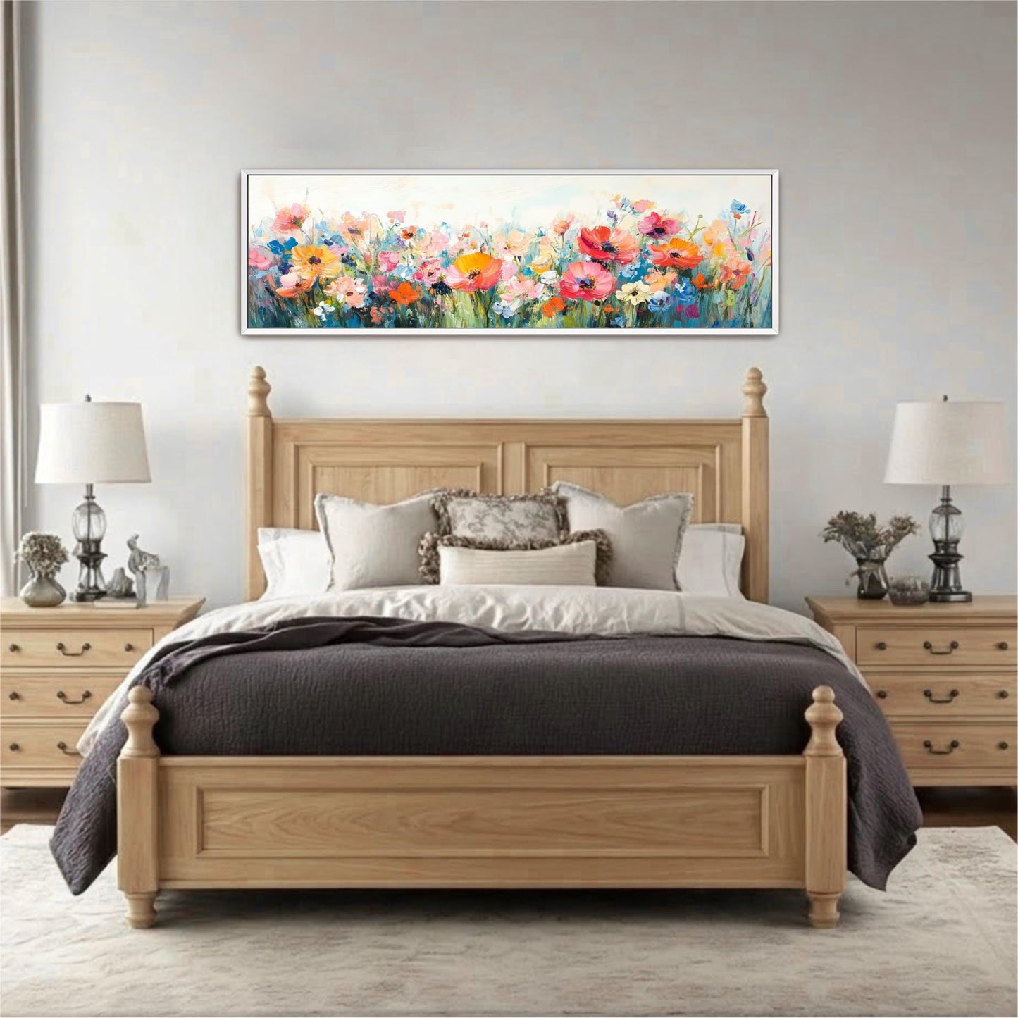 a large wooden bed with a gray comforter and pillows, flanked by two nightstands with lamps. Above the bed is a large painting of a field of colorful flowers.