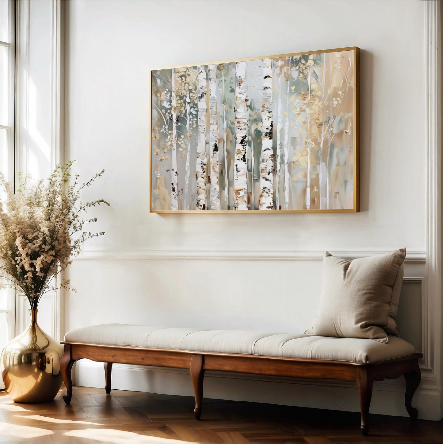 a wooden bench with a beige cushion, positioned in front of a large painting of birch trees on a white wall. The painting is framed in gold and hangs above the bench. The room has a white color scheme, with a large window allowing natural light to illuminate the space.