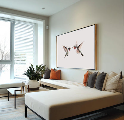 A modern living room with a large window, a white sofa, and a framed artwork of two hummingbirds on the wall.
