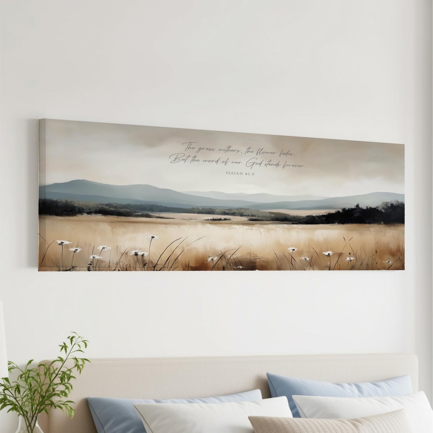 The image is a large canvas print depicting a serene landscape with a field of tall grass and mountains in the background. The text overlay on the canvas reads "The grass waters, but the world of God stands forever".