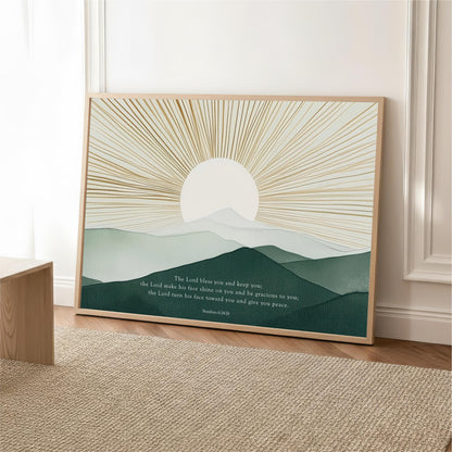 The image is a framed poster with a serene landscape depicting a sun rising over a mountain range. The text on the poster reads "The Lord blows you and keeps you, the Lord makes his face shine on you and begraces to you, the Lord turns his face on you and give you peace."