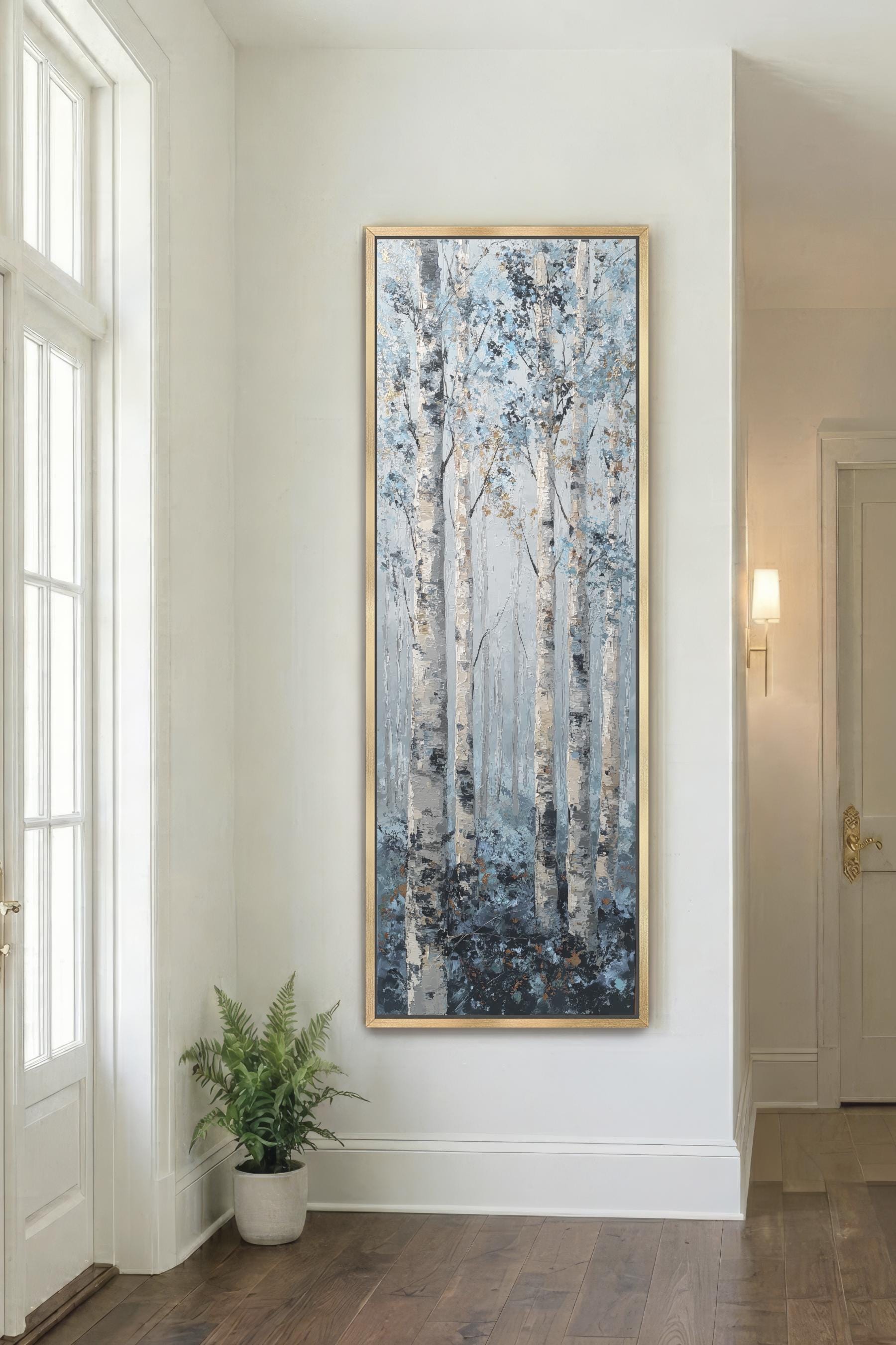 a large painting of birch trees with a blue and white color scheme, hanging on a white wall in a room with a wooden floor.