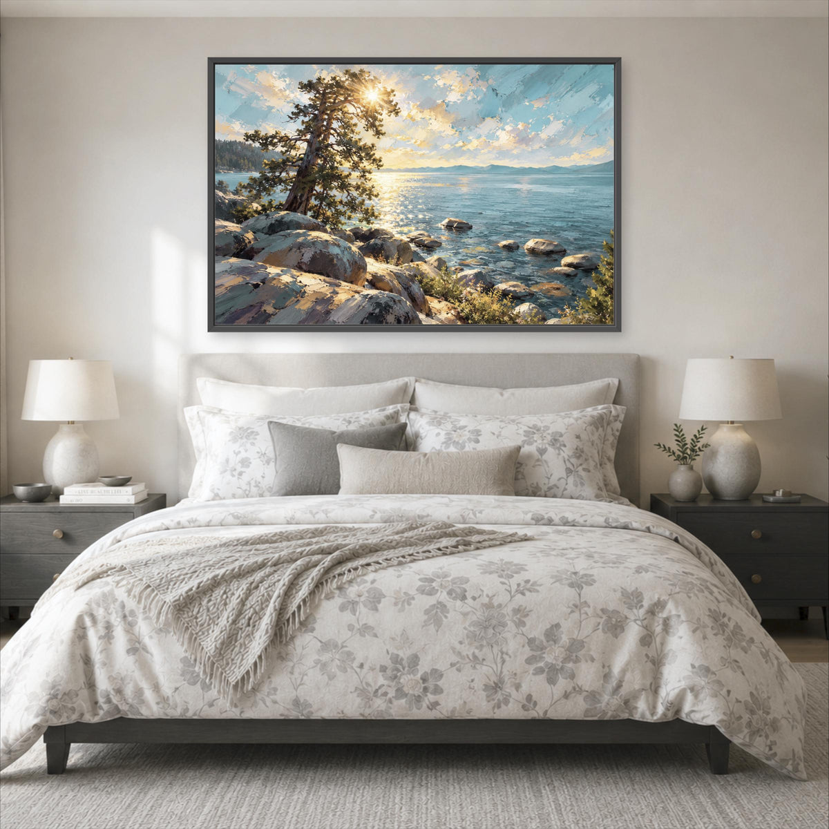 a large, framed painting of a serene landscape with a rocky shoreline and a body of water, hanging above a bed with a floral comforter and pillows.