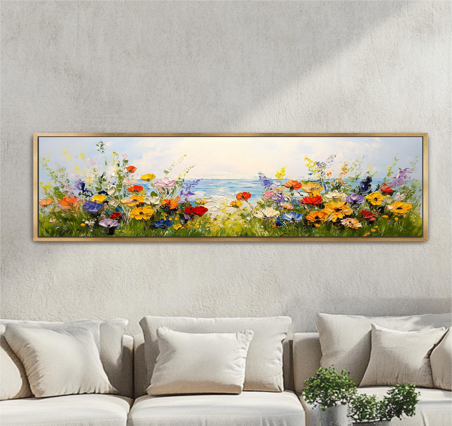A large, framed painting depicting a vibrant field of colorful flowers with a body of water in the background, hanging on a wall above a couch.