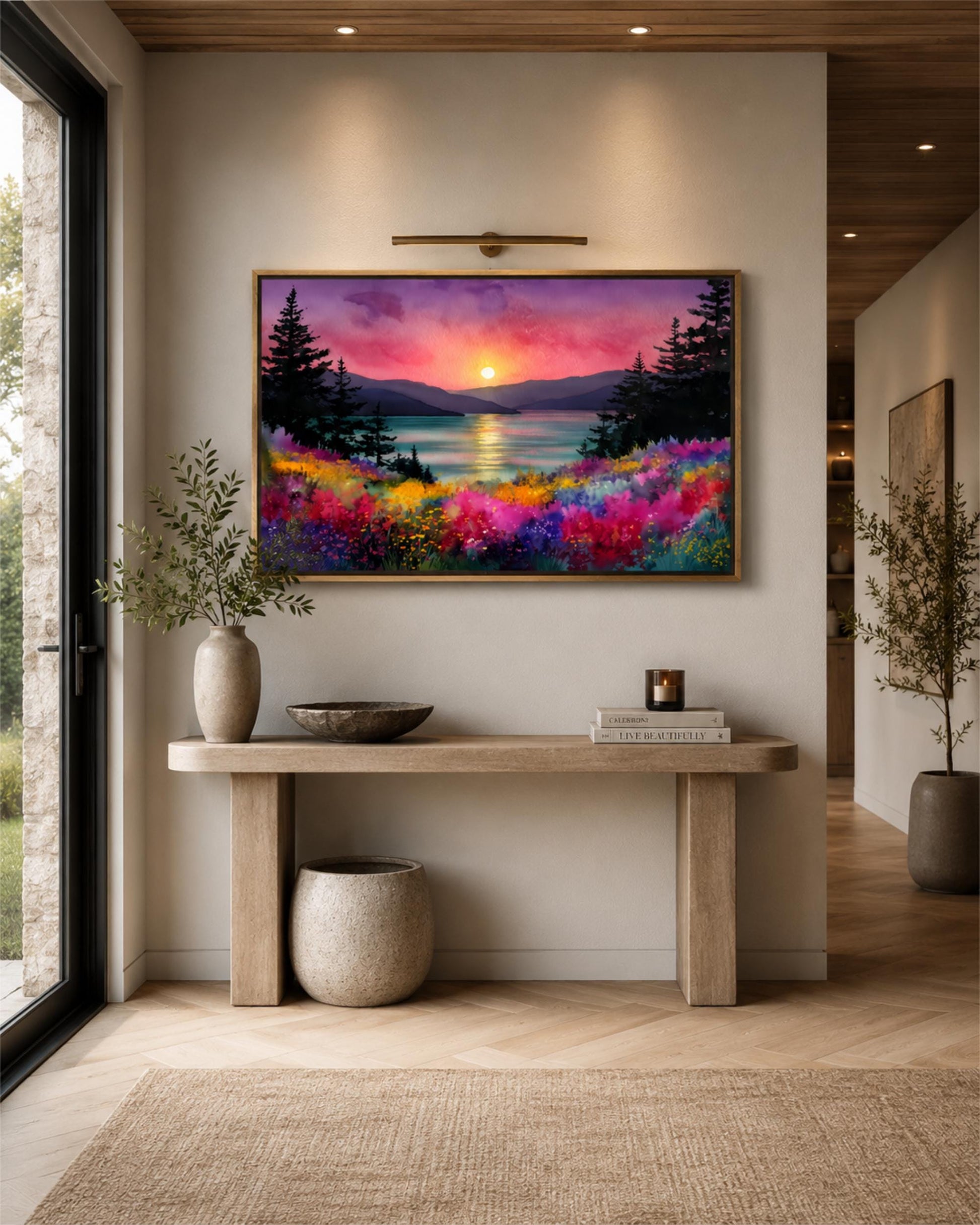 a large, colorful painting of a sunset landscape hanging on a wall above a wooden console table. The table has a bowl, a candle, and a book on it, creating a cozy and inviting atmosphere.