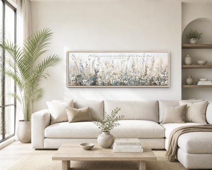 a cozy living room with a large white sofa, a wooden coffee table, and a framed painting of a field of flowers hanging on the wall above the sofa.