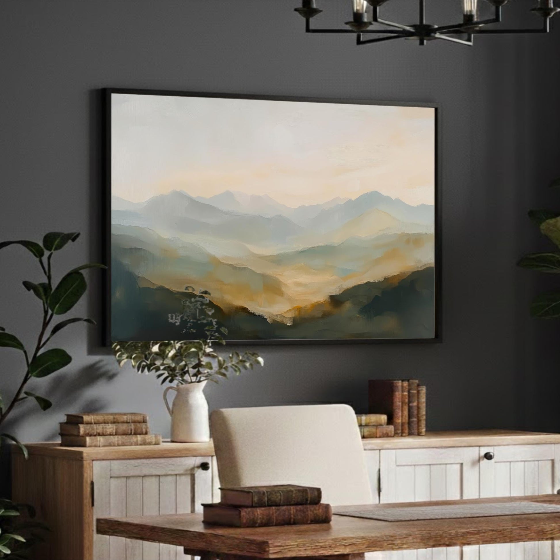 a large landscape painting hanging on a wall above a wooden desk with a white chair. The painting depicts a serene mountain scene with a hazy, golden-hued sky. The desk is set against a dark wall, and there are several books and a plant on the desk.