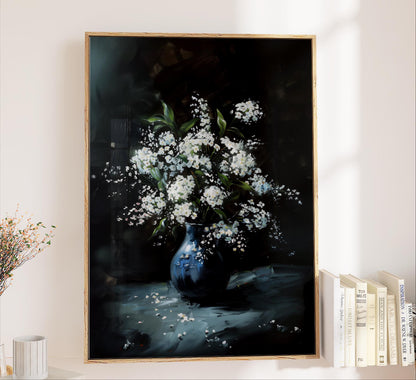 A framed painting of a vase filled with white flowers is displayed on a wall, with a bookshelf filled with books to the right.