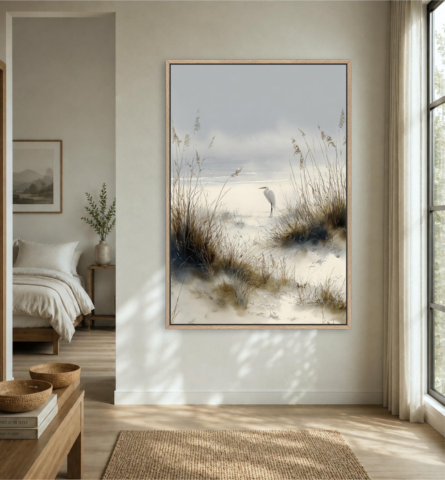 a serene bedroom scene with a large framed painting of a bird standing on a beach, surrounded by tall grasses and a cloudy sky.