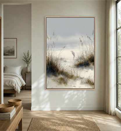 a serene bedroom scene with a large framed painting of a bird standing on a beach, surrounded by tall grasses and a cloudy sky.