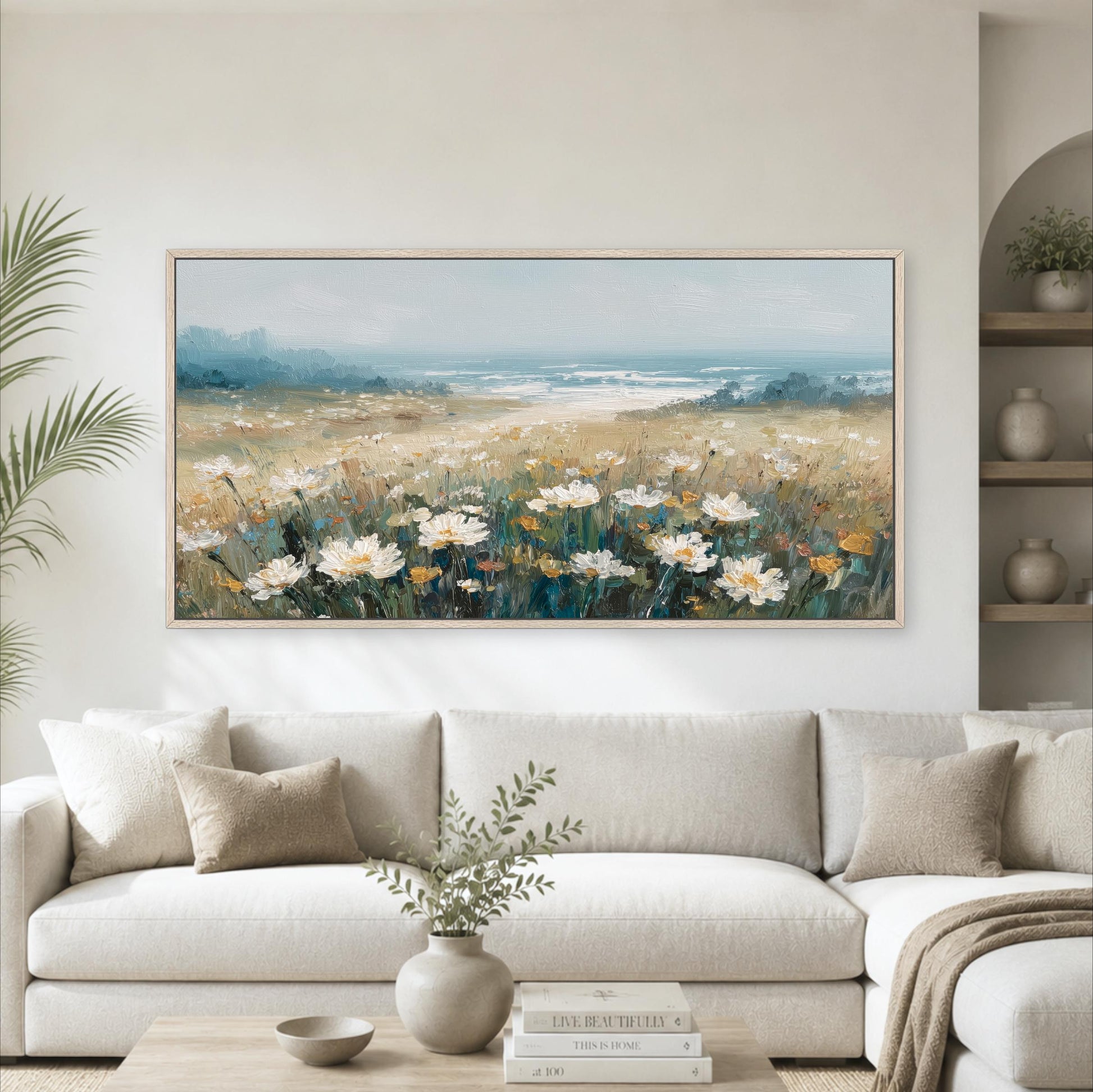 a large painting of a field of flowers hanging on a wall above a white sofa in a living room.