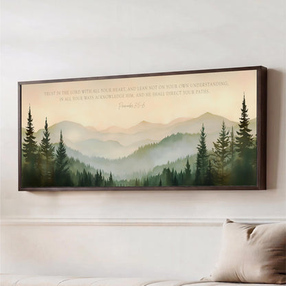The image is a framed print of a mountain landscape with pine trees, hanging on a wall.