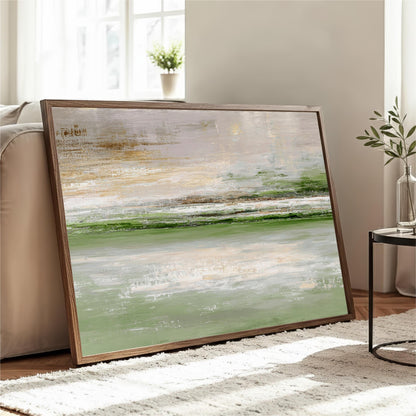 a large, framed painting of a landscape with a green and white color palette, displayed on a wooden floor in a living room setting.
