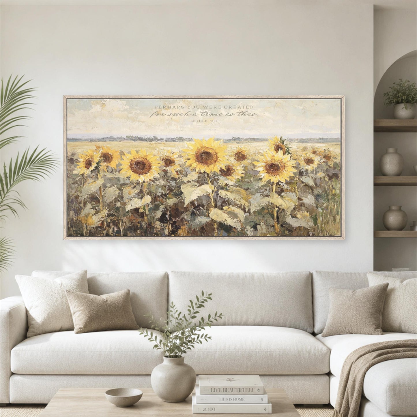 a large painting of a field of sunflowers hanging on a wall above a white sofa in a living room.