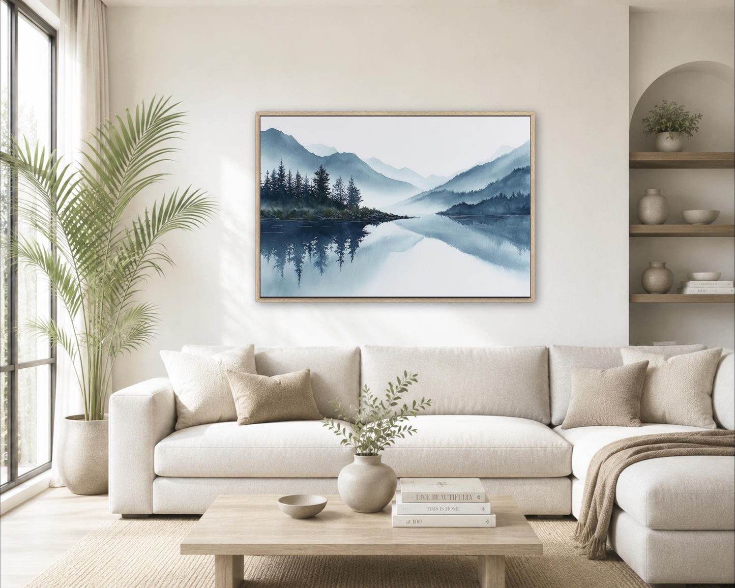 a serene living room with a large painting of a mountain landscape hanging on the wall above a white sofa. The painting features a calm lake surrounded by mountains, creating a peaceful and tranquil atmosphere. The room is decorated with a potted plant, a vase with greenery, and a stack of books on a coffee table. The overall scene conveys a sense of relaxation and harmony.