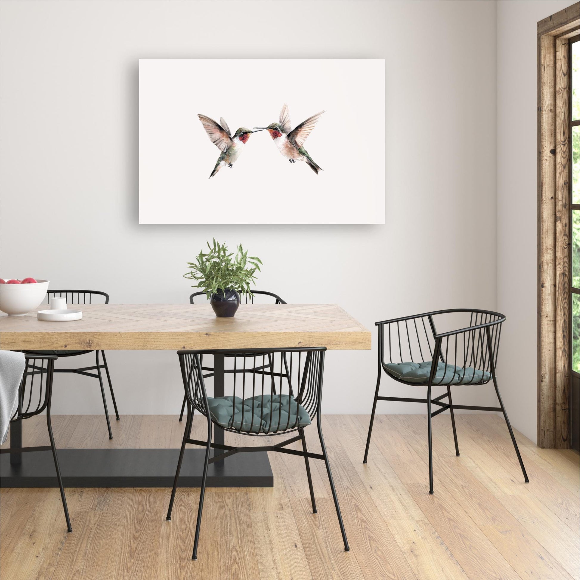 a dining room with a wooden table and chairs, a potted plant, and a framed artwork of two hummingbirds on the wall.