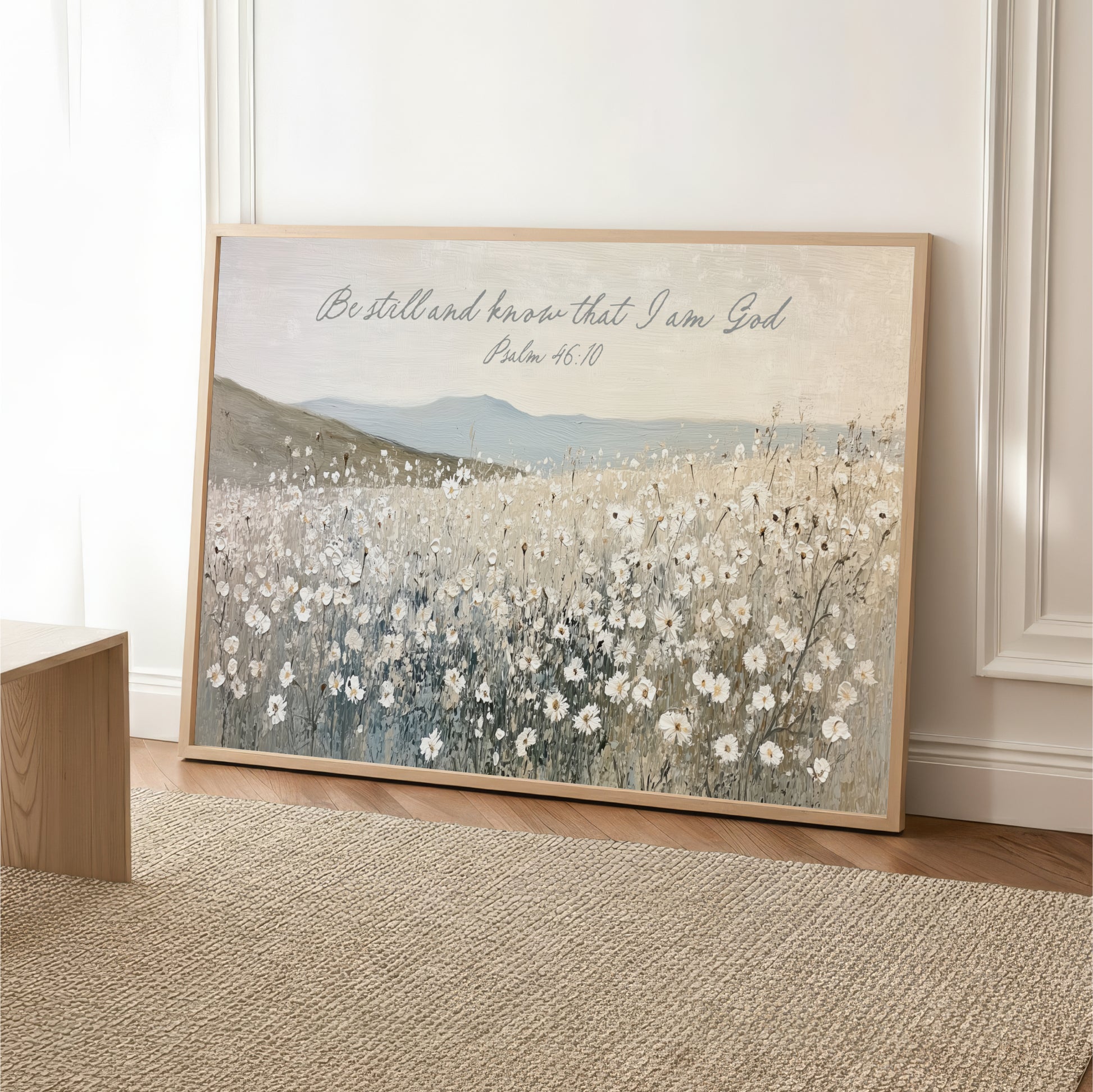 A framed painting depicting a field of white flowers, with a text overlay that reads "Be still and know that I am God" and a Bible verse reference.