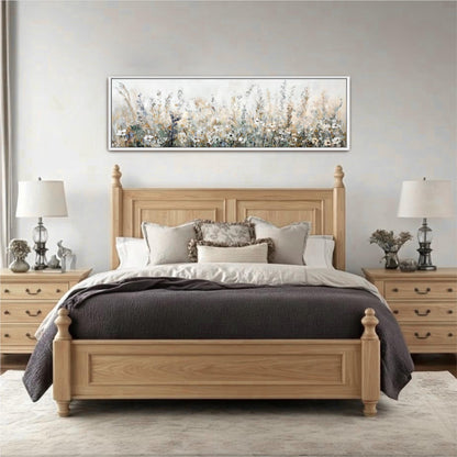 a serene and cozy bedroom with a large wooden bed, a wooden headboard, and a large painting of a field of flowers hanging above it. The bed is adorned with a gray comforter and a gray throw blanket, and the room features a gray rug and two lamps on either side of the bed.