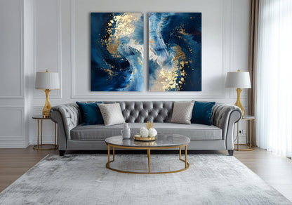 a luxurious living room with a gray tufted sofa, a round glass coffee table, and two gold-framed lamps on either side of the sofa. Above the sofa, there are two large abstract paintings with blue and white swirls and gold accents, creating a striking focal point in the room.