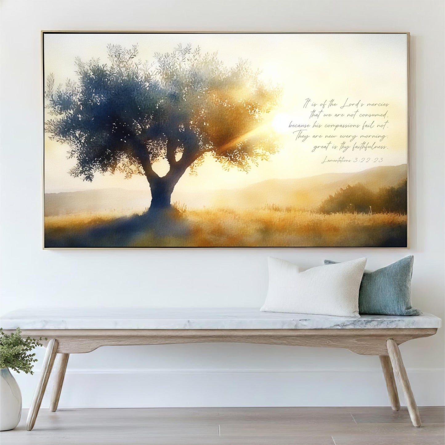 a large, framed painting of a tree with a golden sunset in the background, hanging on a white wall above a wooden bench with pillows.