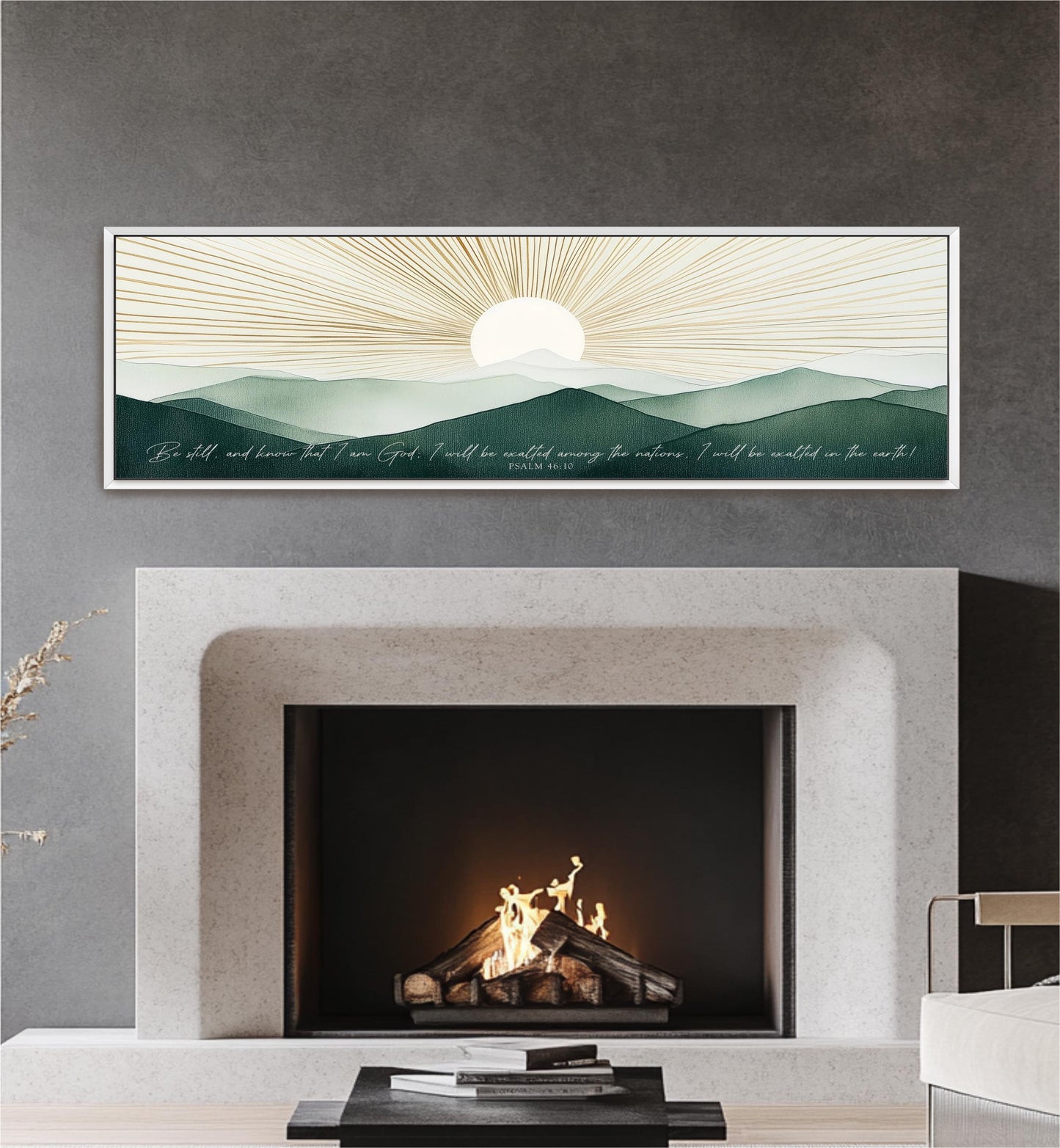 a fireplace with a warm fire burning inside, set against a backdrop of a serene landscape with mountains and a sun-like design. Above the fireplace, there is a framed artwork depicting a sunrise or sunset over a mountainous terrain. The artwork is framed in a white frame and hangs on a gray wall.