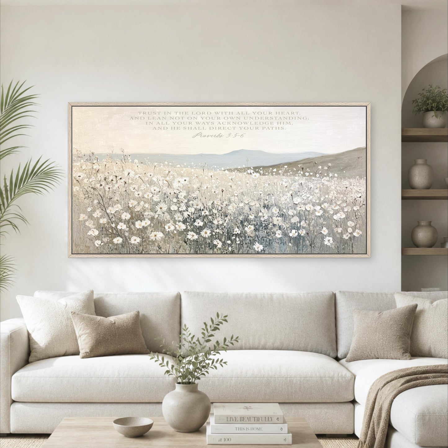 a large framed painting of a field of flowers hanging on a wall above a white sofa in a living room.