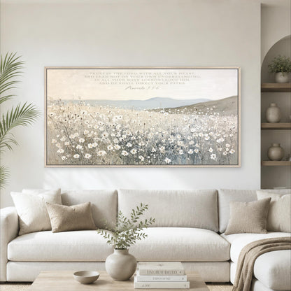 a large framed painting of a field of flowers hanging on a wall above a white sofa in a living room.