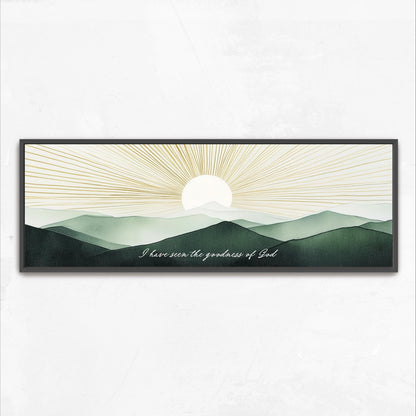 A framed artwork depicting a serene landscape with mountains and a sun rising over the horizon.