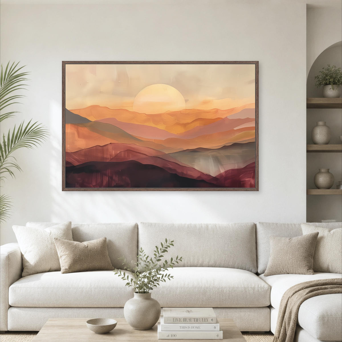 a large, framed painting of a sunset over mountains hanging on a wall in a living room.
