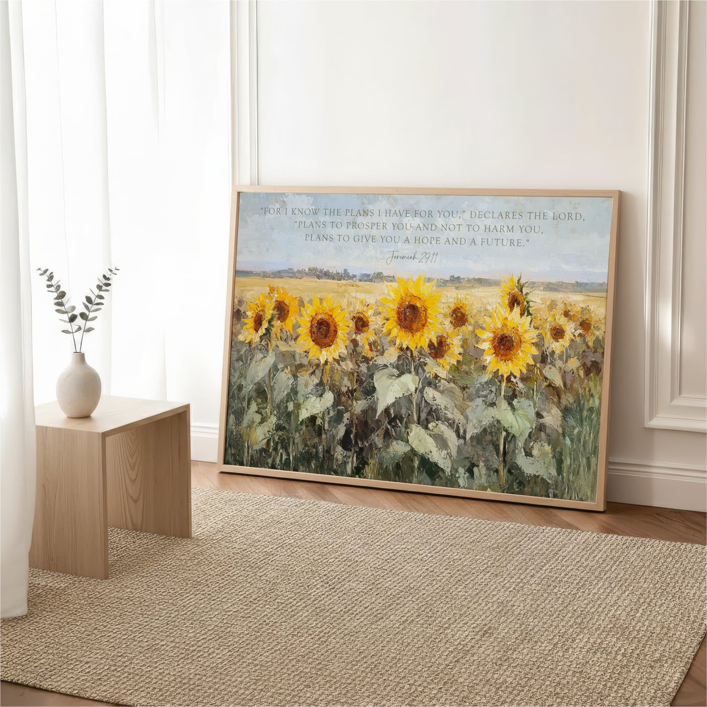a large painting of a field of sunflowers, with a vase of greenery on a wooden table in the foreground.