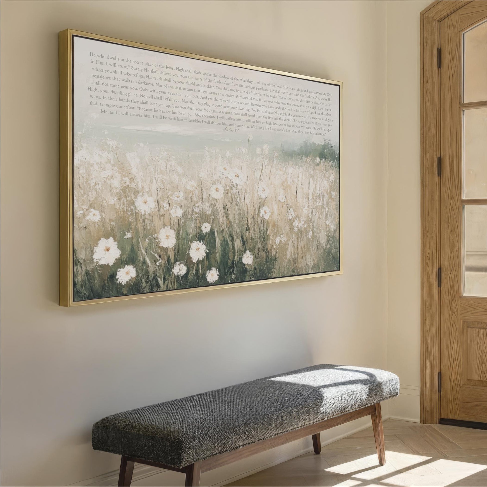 a large framed painting of a field of white flowers hanging on a wall, with a gray bench placed in front of it.