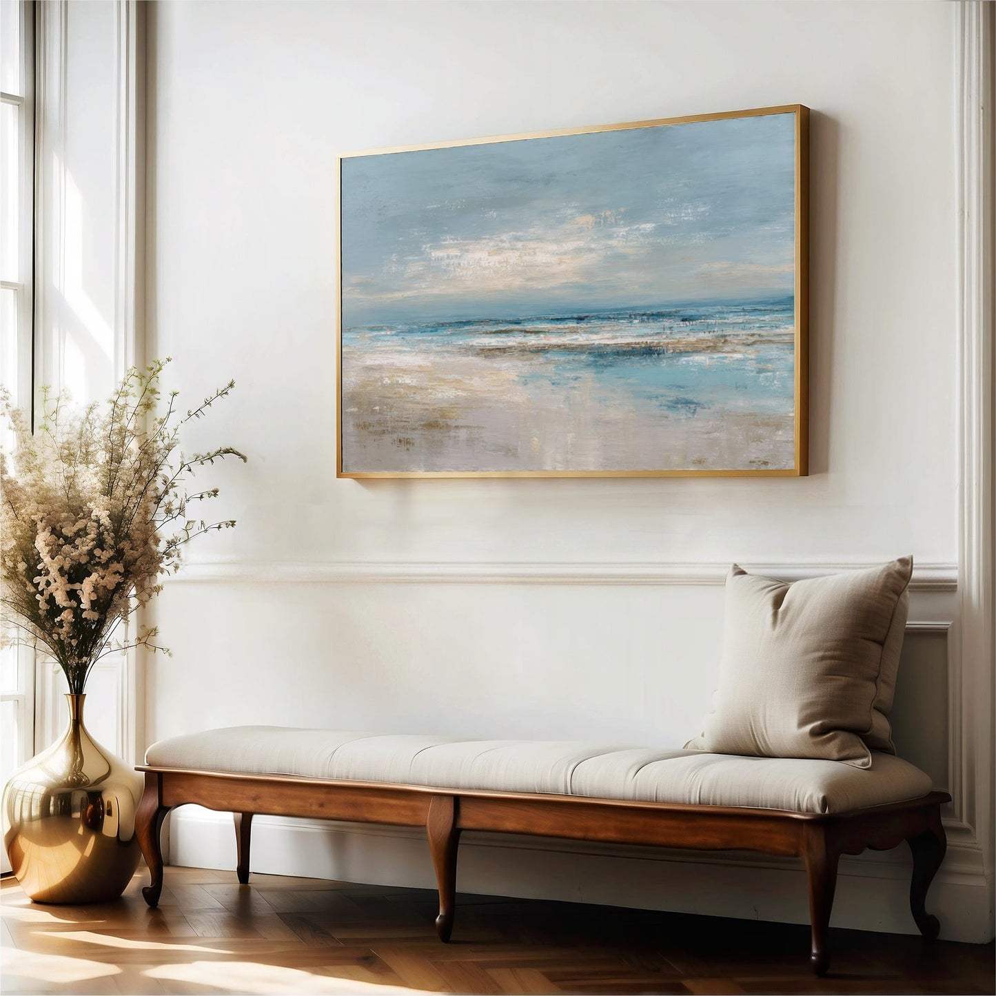 a large painting of a beach scene hanging on a white wall, with a wooden bench and a vase of flowers placed in front of it.