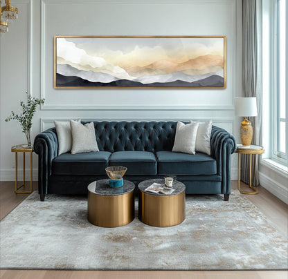 A modern living room with a blue tufted sofa, two round coffee tables, and a large landscape painting on the wall.