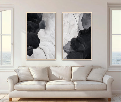 two large abstract paintings hanging on a wall above a beige sofa in a living room.