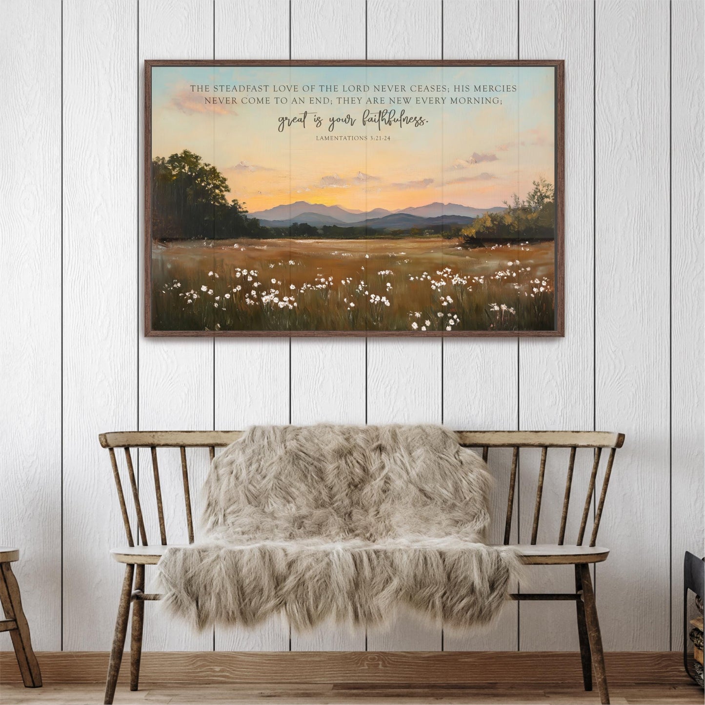 a wooden bench with a furry blanket draped over it, set against a serene landscape of a field with white flowers and a sunset in the background. Above the bench, there is a framed painting depicting a pastoral scene with mountains in the distance.