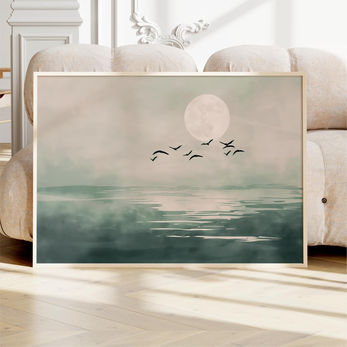 A framed painting depicting a serene landscape with a large moon and a flock of birds flying over a calm body of water.