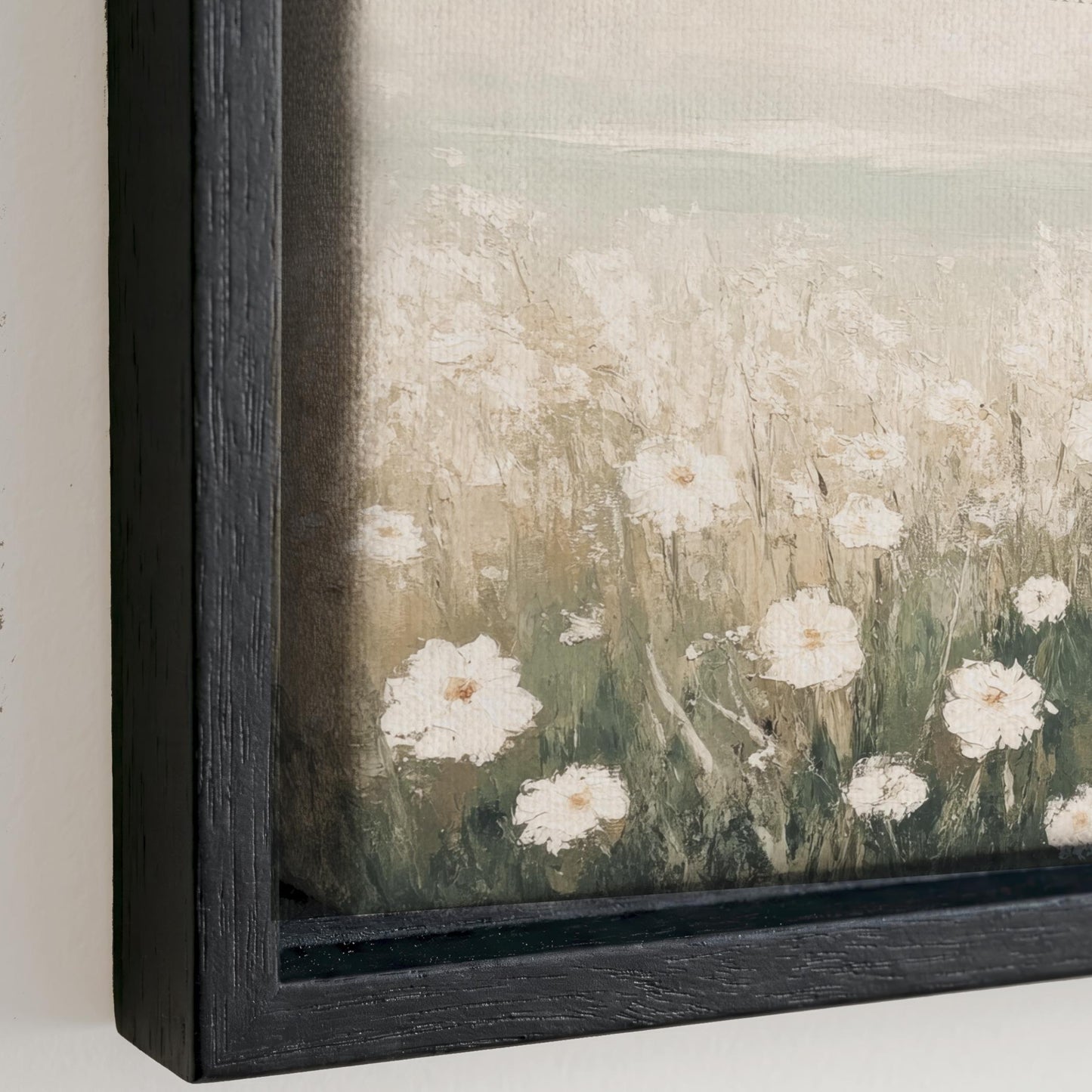 The image is a painting of a field of white flowers, with the flowers appearing to be in various stages of bloom. The painting is framed in a black frame and is displayed on a wall.