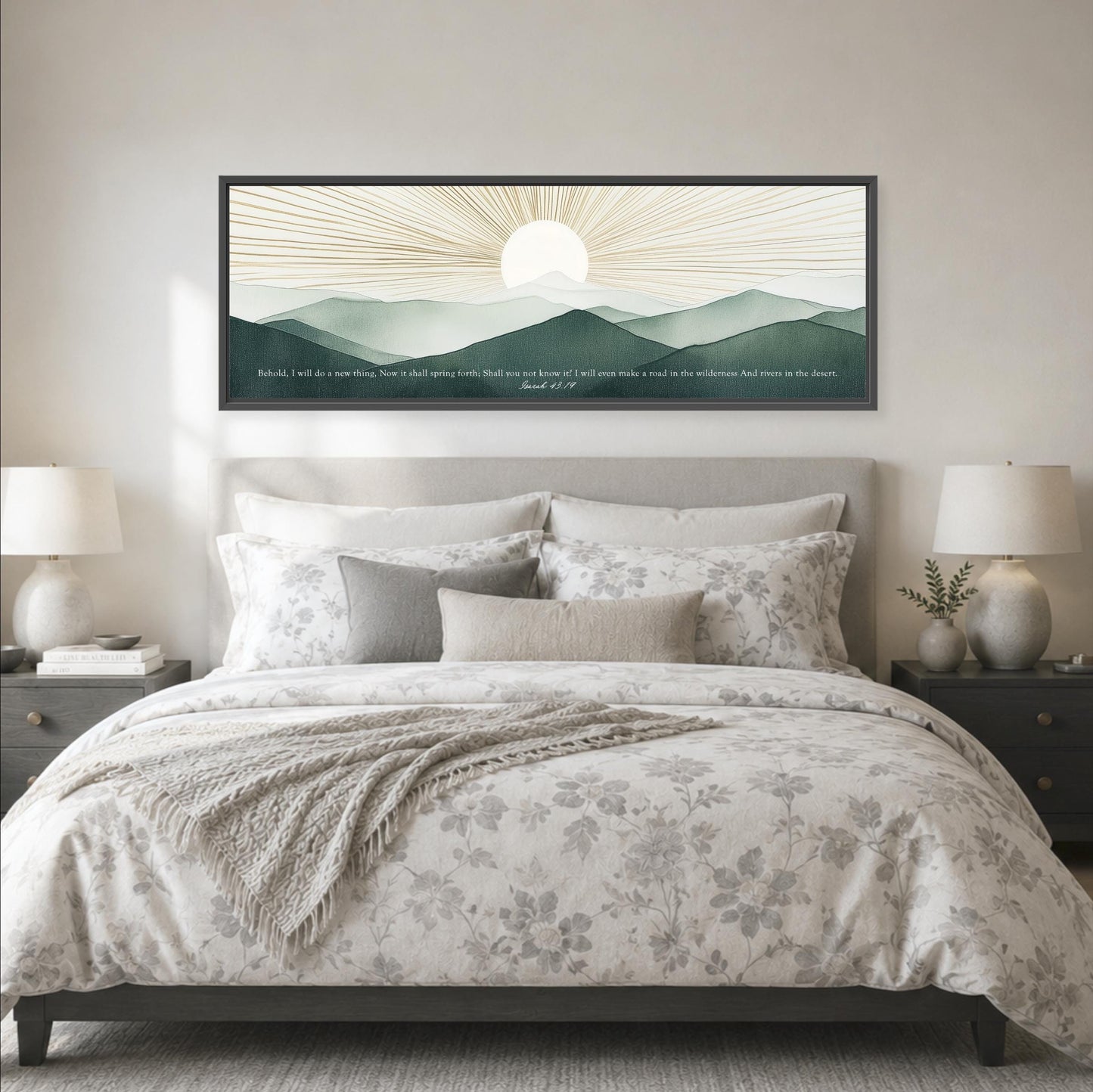 a large bed with a floral bedspread and pillows, flanked by two nightstands with lamps. Above the bed is a framed artwork depicting a mountain landscape with a sun in the sky.
