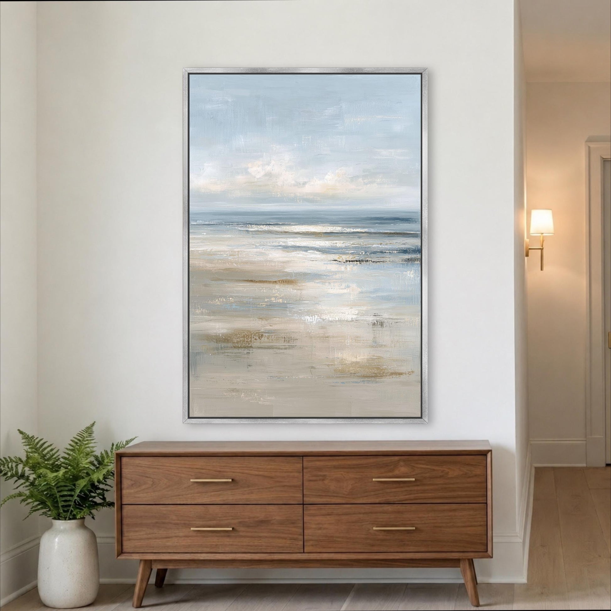 a large painting of a serene landscape hanging on a white wall above a wooden dresser with four drawers. Abstract Ocean Framed Canvas Portrait Art, Coastal Seascape Muted Light Blue Beige, Modern Beach Landscape Artwork, Cottage Beach Print