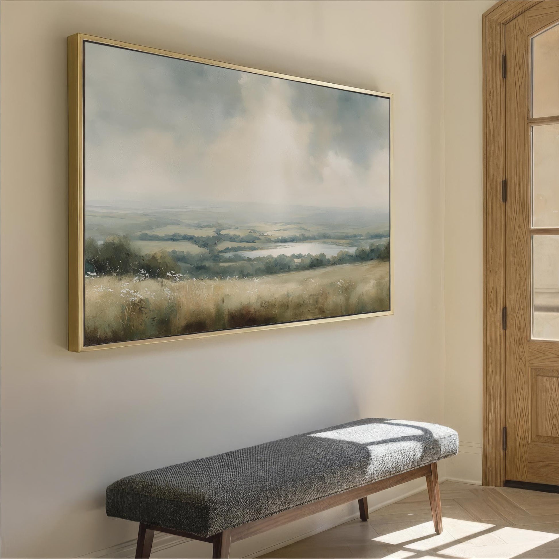 a large landscape painting hanging on a wall, with a wooden bench placed in front of it.