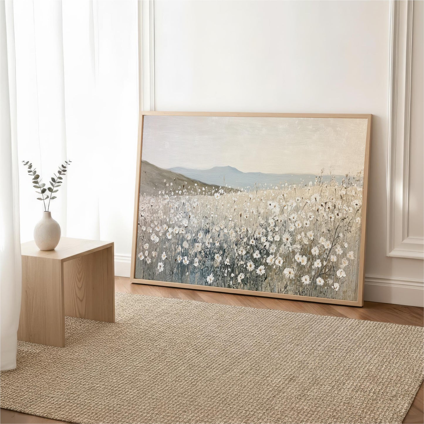 a large painting of a field of flowers, with a vase of flowers placed on a wooden table next to it.