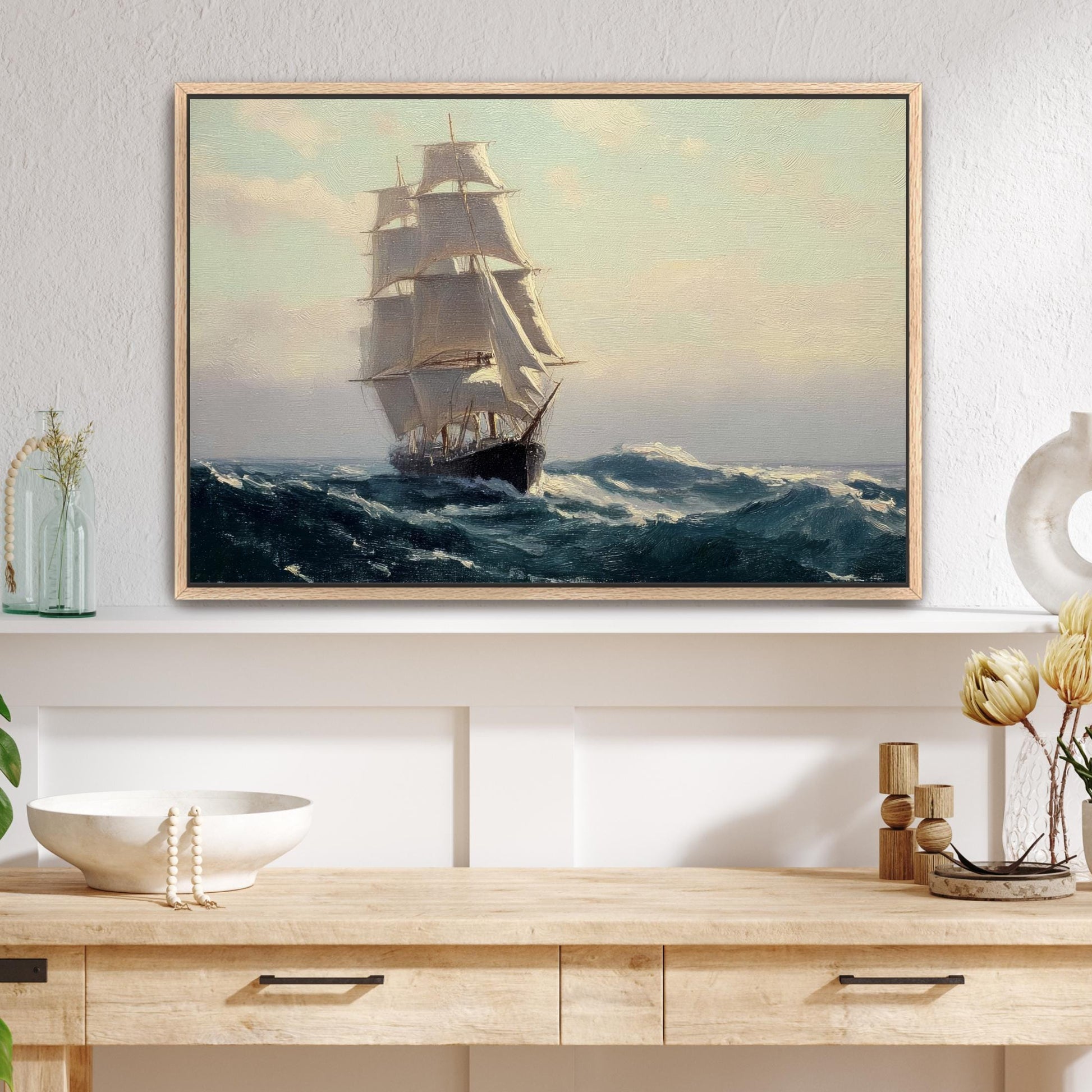 a large painting of a sailing ship on the ocean, hanging on a wall above a wooden table with various decorative items on it.
