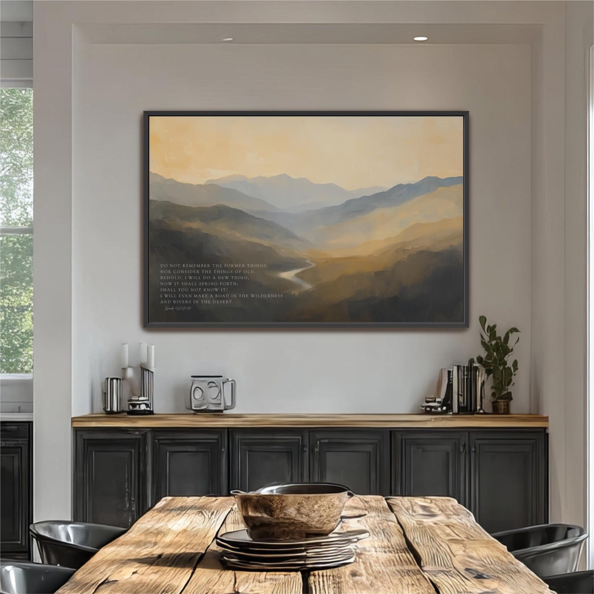 a large painting of a mountainous landscape hanging on a wall above a wooden dining table with a bowl on it.