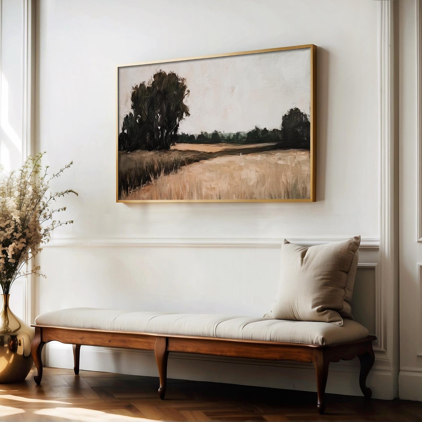 a large painting of a field hanging on a white wall above a wooden bench with a white cushion.