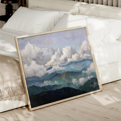 a framed painting of a mountainous landscape with a cloudy sky, placed on a bed in a bedroom setting.