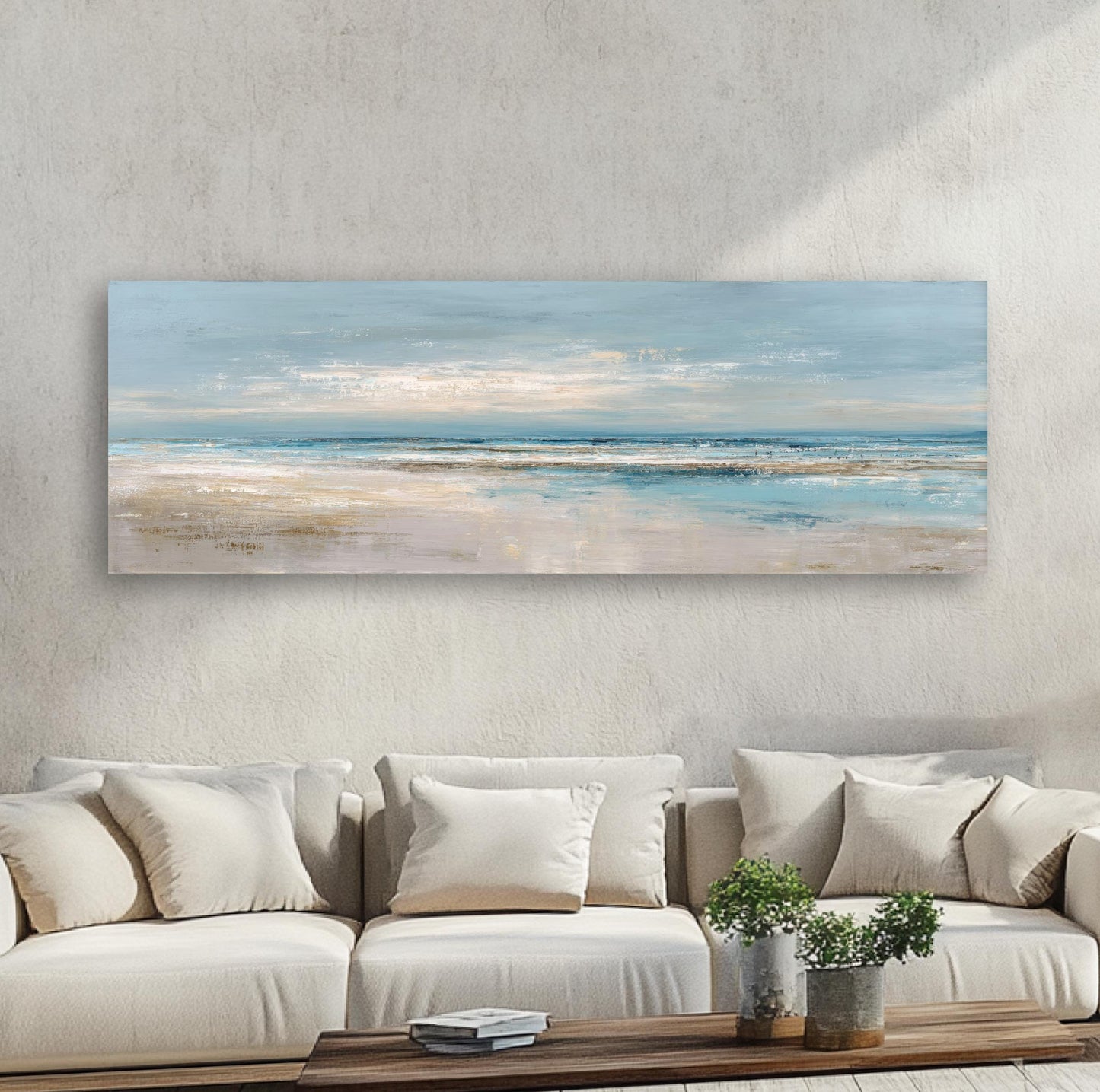 a large, rectangular painting of a beach scene hanging on a wall above a beige sofa with white pillows.