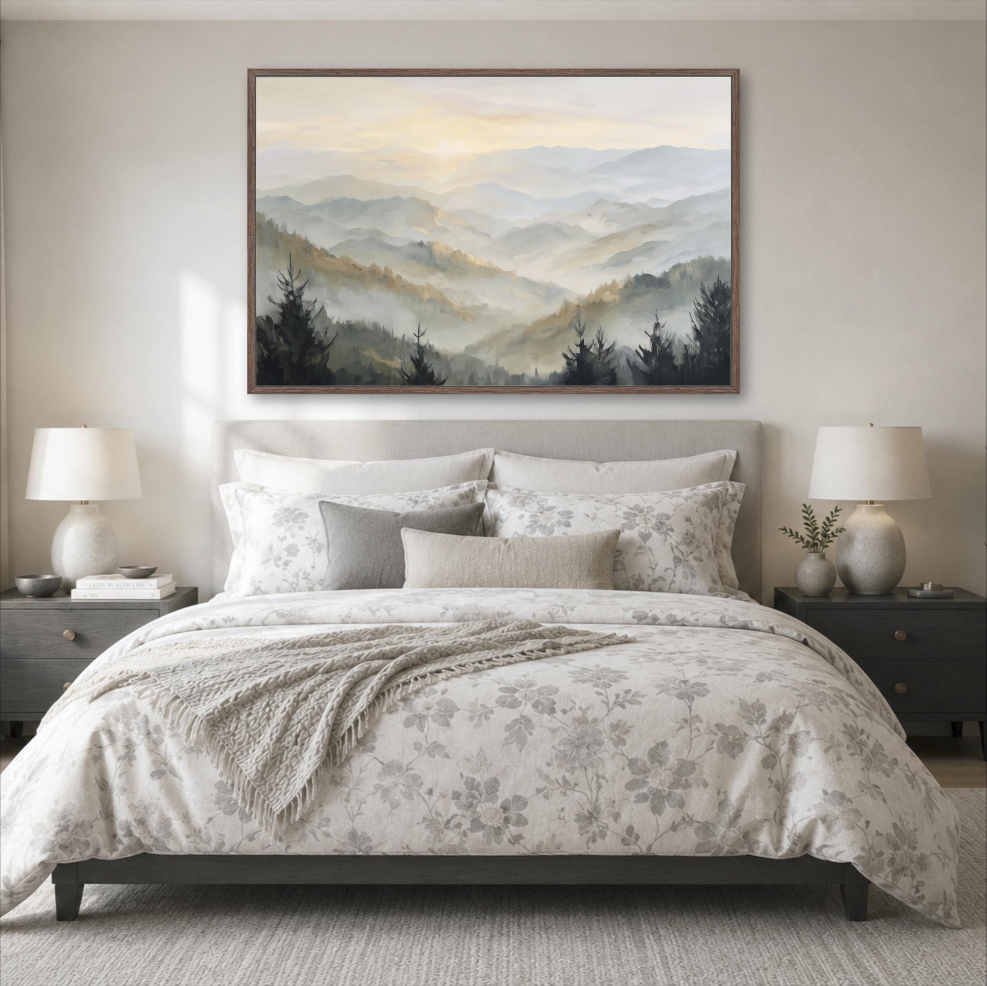 a serene bedroom scene with a large bed adorned with a floral comforter and pillows, flanked by two nightstands with lamps. Above the bed, a large framed landscape painting of a mountain range with a hazy, misty atmosphere is displayed on the wall.